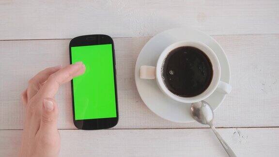 女孩一边喝咖啡一边用绿色屏幕的手机
