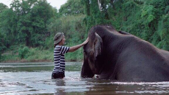 旅行者骑着大象在河里给大象洗澡