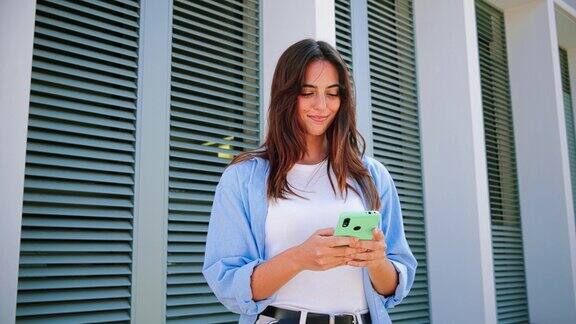 微笑的年轻女子使用手机应用发短信玩游戏网上购物订购送货快乐的千禧少女分享社交媒体拿着智能手机在户外