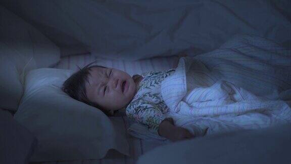 亚洲婴儿面对悲伤的情绪晚上在床上哭泣