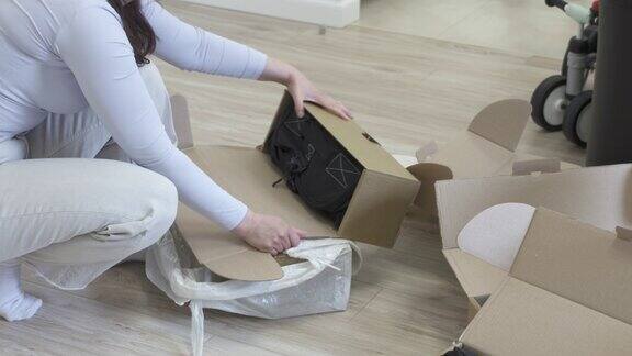 女人在家里拆箱拆箱从网上商店送的新旅行袋包裹