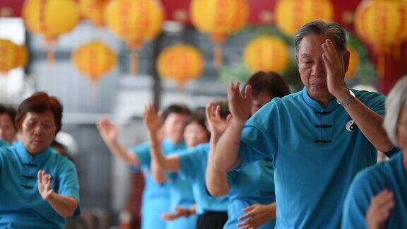 一名老人在一群人中间打着太极拳