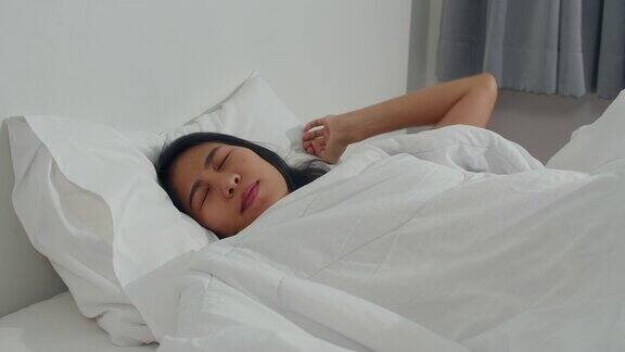 日本亚裔妇女在家睡觉年轻的亚洲女孩躺在床上感到快乐放松休息早上在家里的卧室里感到舒适和平静4k分辨率和慢动作拍摄