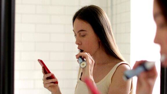 年轻女子用智能手机刷牙