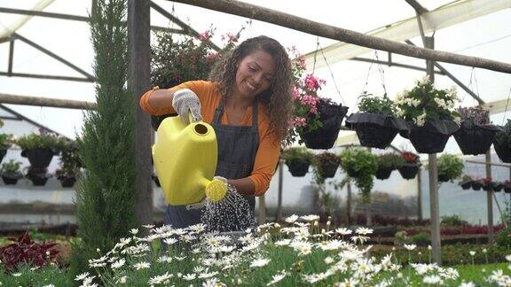 快乐的女园丁在花园中心浇灌植物
