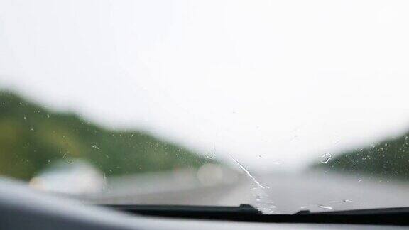 在能见度有限的情况下驾驶汽车:大雨雨刷清洁挡风玻璃高速公路上迎面而来的车辆开着前灯恶劣天气条件下的道路安全从车内看