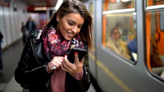 在地铁站使用手机的女性通勤者