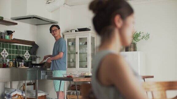 一名男子在厨房做饭一名女子拿着平板电脑微笑着交谈