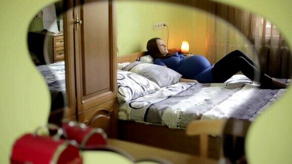 一名年轻孕妇躺在绿色卧室的枕头上