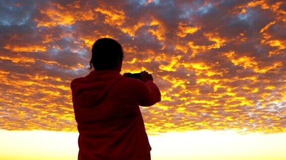一个女人在用4k慢镜头拍摄加州上空橙色的血腥云