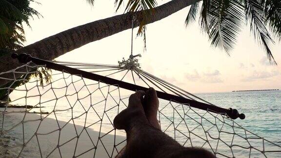 马尔代夫天堂般的海滩上一名男子躺在吊床上