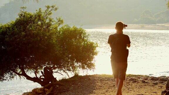 一名旅行者在山间的湖边拍摄美丽日落的视频片段