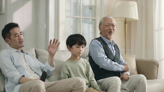 亚洲儿子父亲和祖父正在看电视上的足球比赛直播