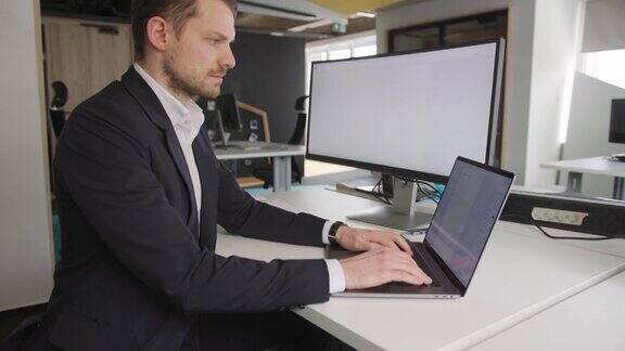 一个商人坐在瑜伽球上在办公室里用笔记本电脑工作