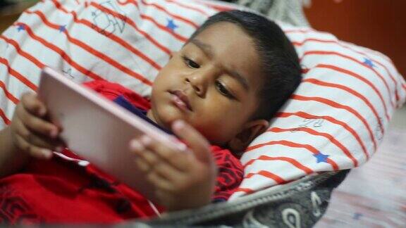 一个孩子躺在自制的吊床上用智能手机看动画片孩子们玩智能手机手机和网络成瘾