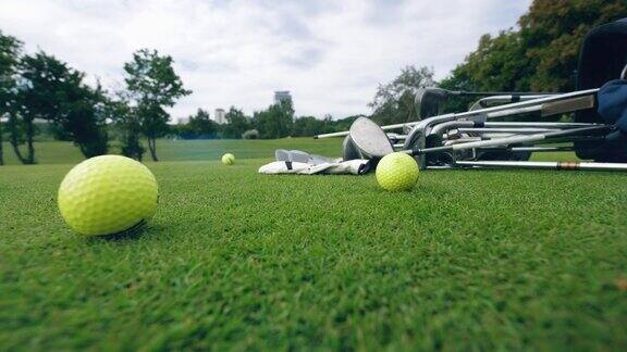 黄色的球和金属球杆躺在高尔夫球场上