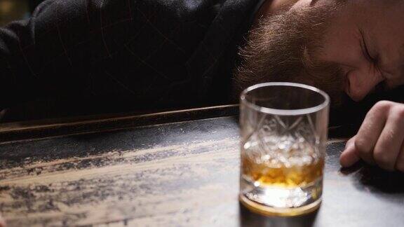 一个醉汉在酒吧喝着威士忌睡着了