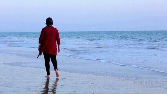 在海滩上赤脚行走的老妇人