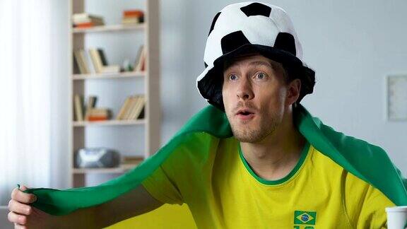 巴西球迷在电视上看足球比赛吹着球迷的喇叭欢呼