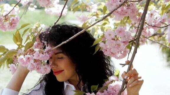 美丽的微笑黑发享受樱花的气味