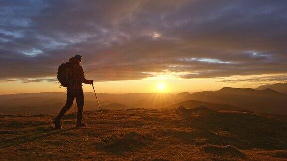 男性徒步旅行者在日落时到达山顶