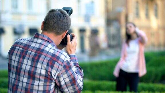 女模特摆姿势给男摄影师拍照在夏季公园拍照