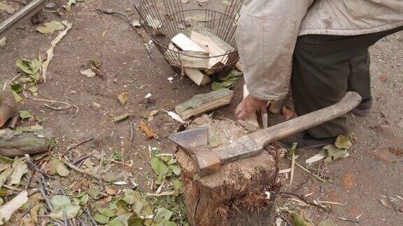 在一个贫穷的俄罗斯村庄爷爷用斧头在树桩上砍柴秋天村院子为冬天砍柴