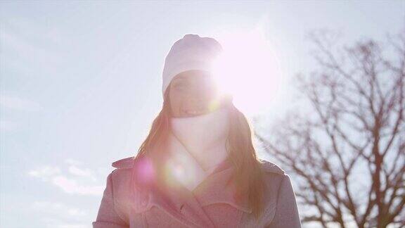 慢镜头:微笑的年轻女子在阳光明媚的冬天吹雪花