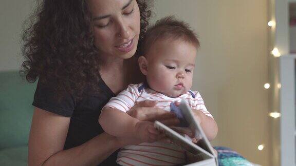 年轻慈爱的母亲给可爱的宝宝读睡前故事书