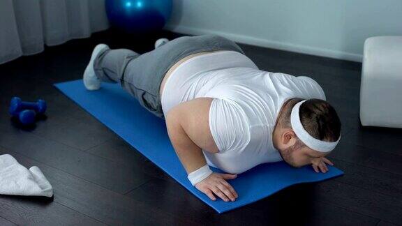 肥胖虚弱的男子躺在瑜伽垫上无法做平板支撑运动保健