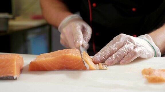 在寿司吧里戴着手套的寿司厨师切鲜鲑鱼的特写