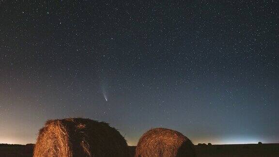 彗星Neowisec2020F3在夏季农田干草堆上空的夜空中夜晚的星星在乡村景观与收获后的干草捆农业概念4K时间间隔