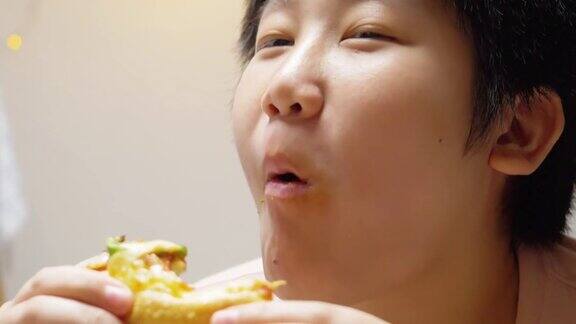 亚洲男孩晚上在家吃披萨生活理念