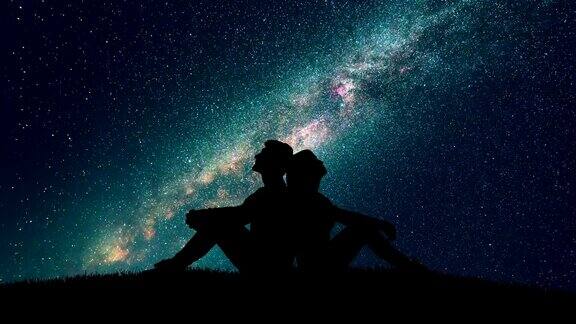 这对夫妇坐在草地上背景是繁星点点的天空时间流逝