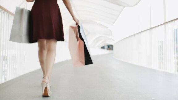 自信的女人走在购物中心购物袋