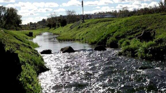 纯净的淡水在城市环境中流过纯净的河流冲刷着绿草的巨石和陡峭的河岸
