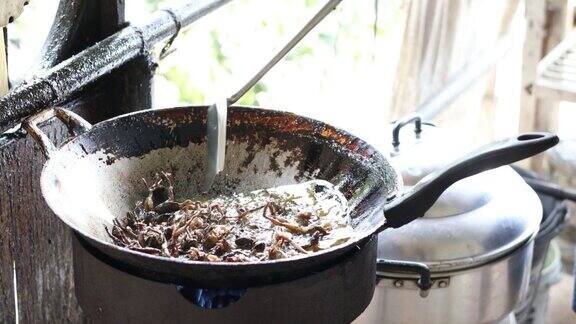 一个厨师正在旧锅里的热油里煎一只小青蛙