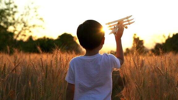 可爱的亚洲小孩在日落时分的稻田里玩玩具飞机
