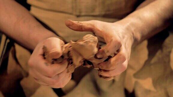 陶工用手指捏着一块中等大小的棕色粘土