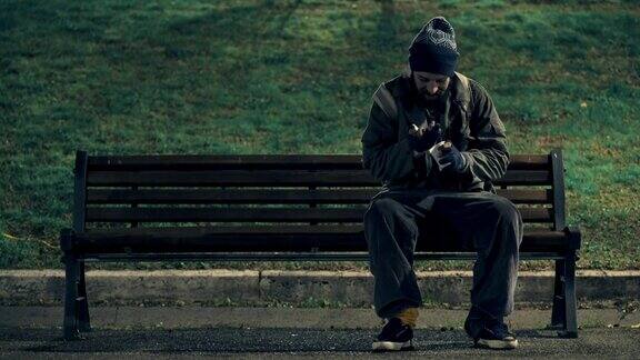 可怜的乞丐晚上坐在长凳上数着他的布施