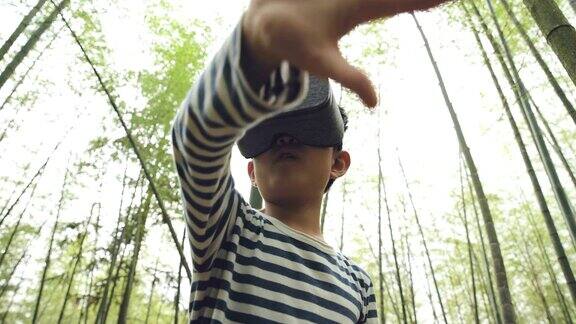 小男孩戴着VR设备在竹林里玩耍