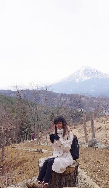 4K亚洲女子在冬季川口湖和富士山旅游时使用手机