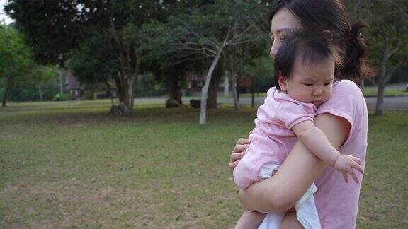 在公园里年轻的亚洲母亲抱着她的小女儿