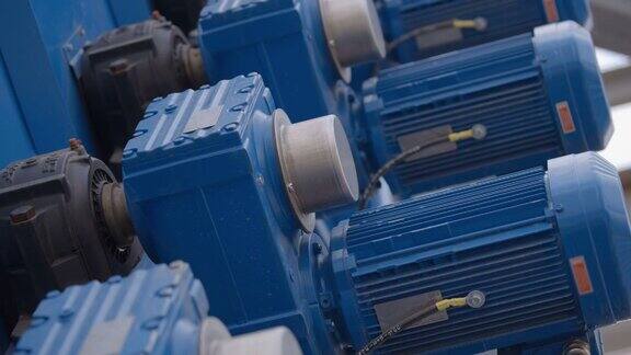 一排排蓝色的大功率工业电动机在一家新工厂的生产线上