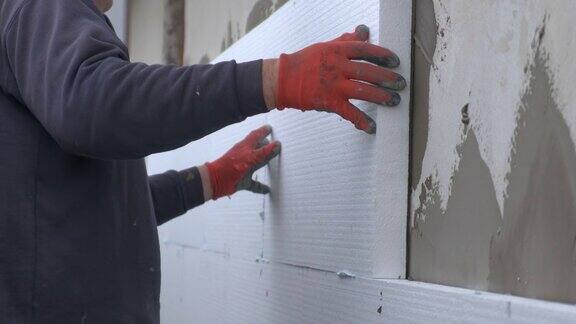 建筑工人在房屋外立面上安装保温泡沫塑料