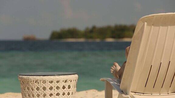 年轻的家庭夫妇日光浴和喝彩色鸡尾酒在热带海滩情侣在蜜月异国度假躺在海边的躺椅上的阳光度假