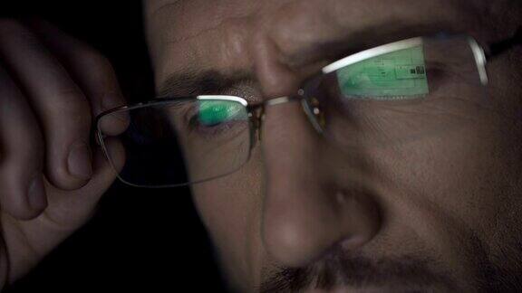 笔记本电脑屏幕上的文件反射在眼镜上侦探在夜间工作