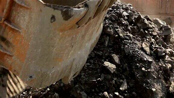 一个工业挖掘机的桶特写挖掘机在自卸车中装载原料在铁矿采石场工作