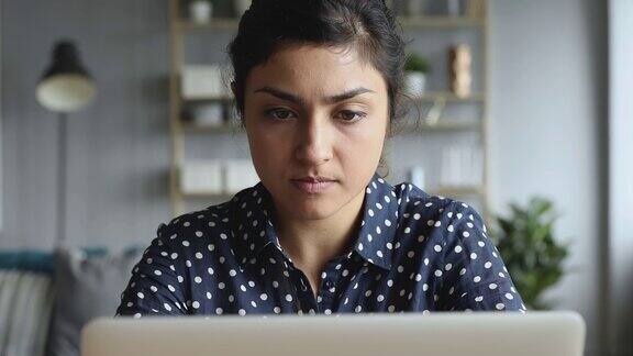 体贴关切的印度妇女在电脑上思考解决问题