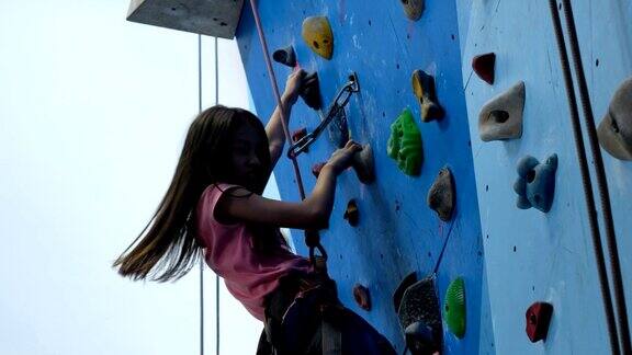 女孩穿着攀岩鞋和身体背带爬攀岩墙特写